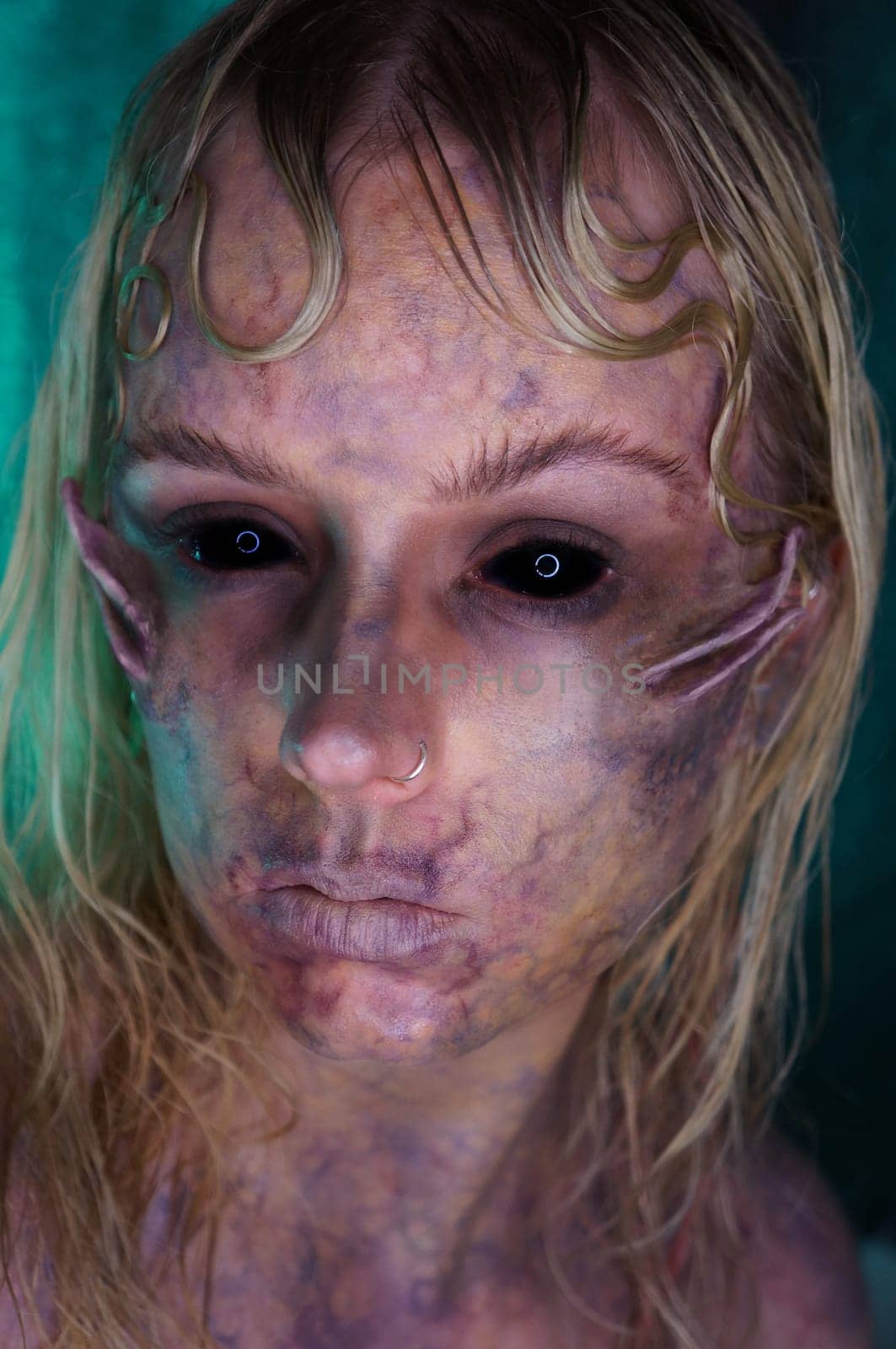 young blond woman infront of black background with scary sfx makeup
