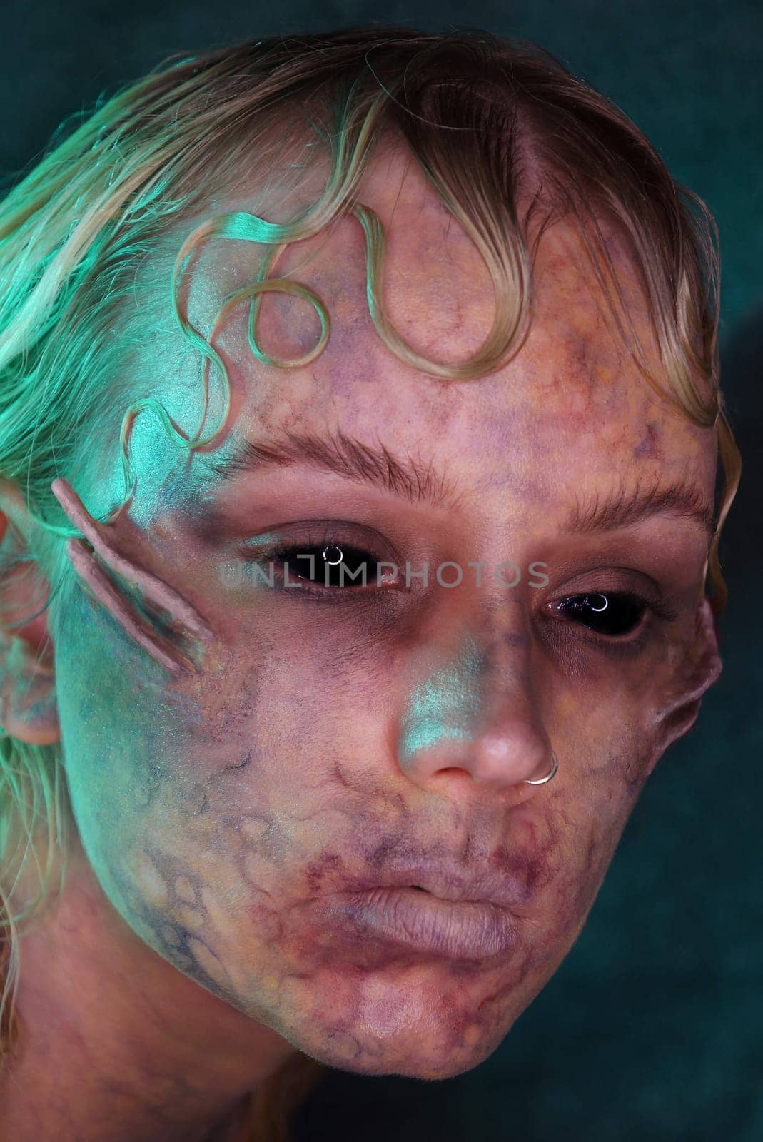young blond woman infront of black background with scary sfx makeup