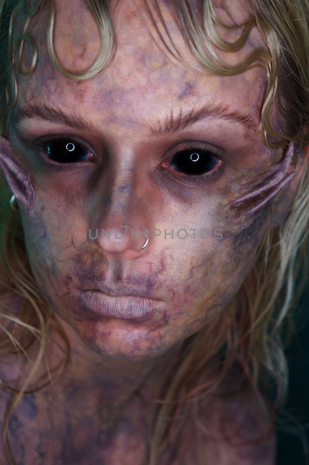 young blond woman infront of black background with scary sfx makeup