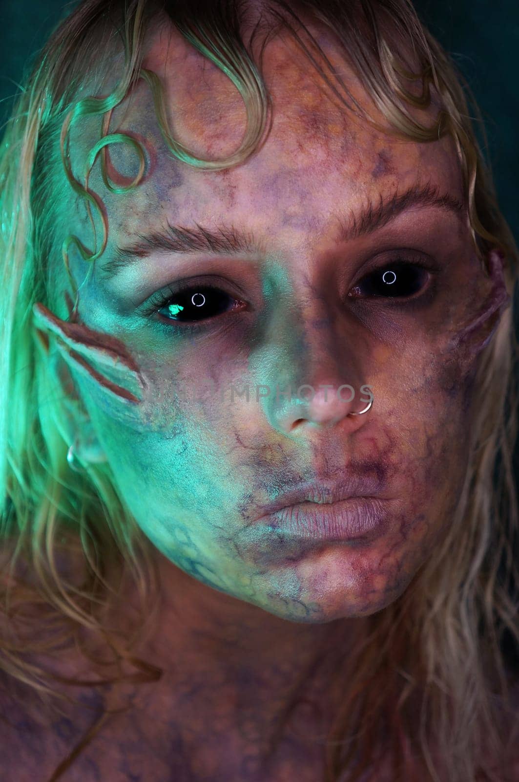 young blond woman infront of black background with scary sfx makeup