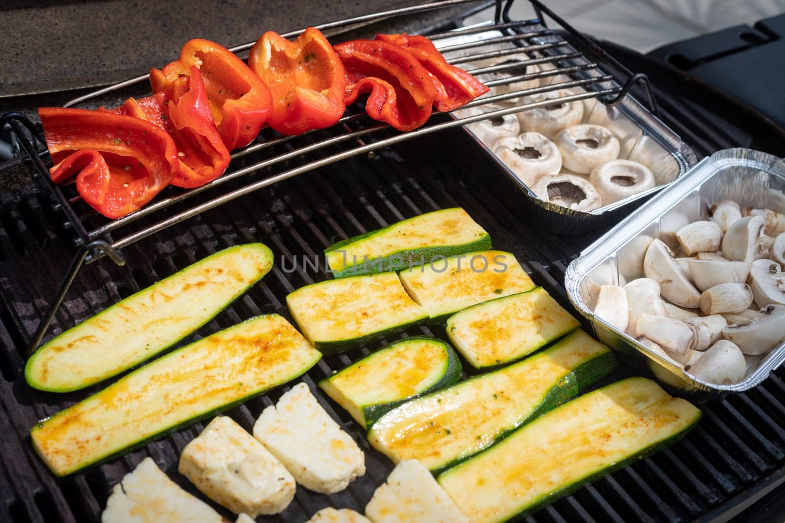 Close up of cheese and vegetables on gas grill. Summer time, outdoors.