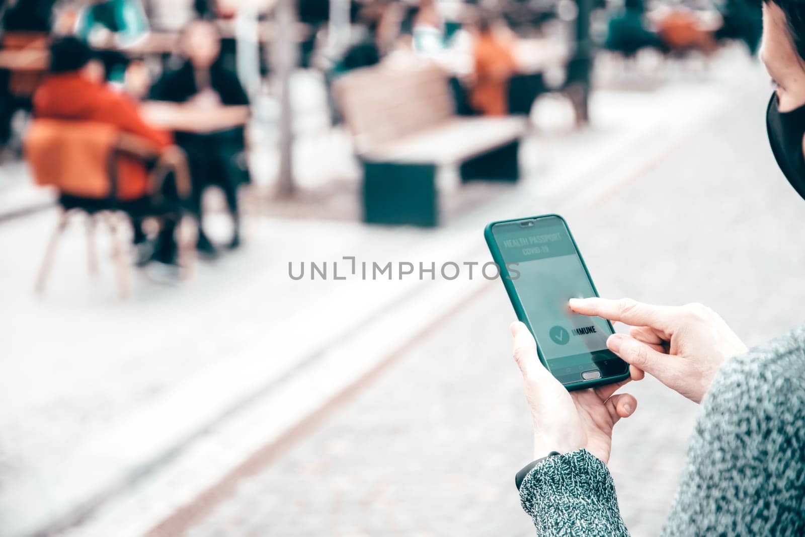 Vaccinated person using immunization certificate on smartphone at the restaurant or terrace.