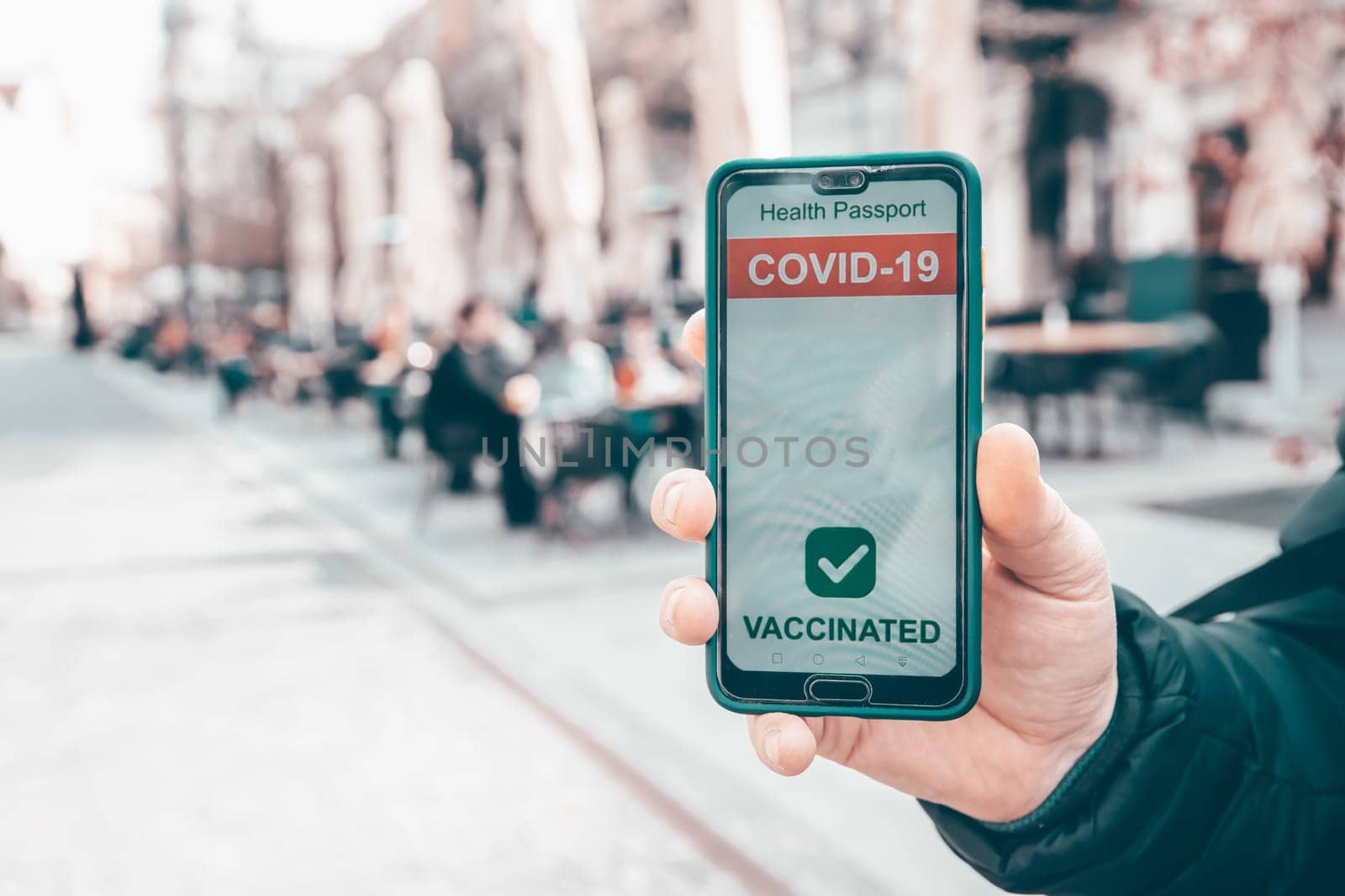 Vaccinated person using immunization certificate on smartphone at the restaurant or terrace.