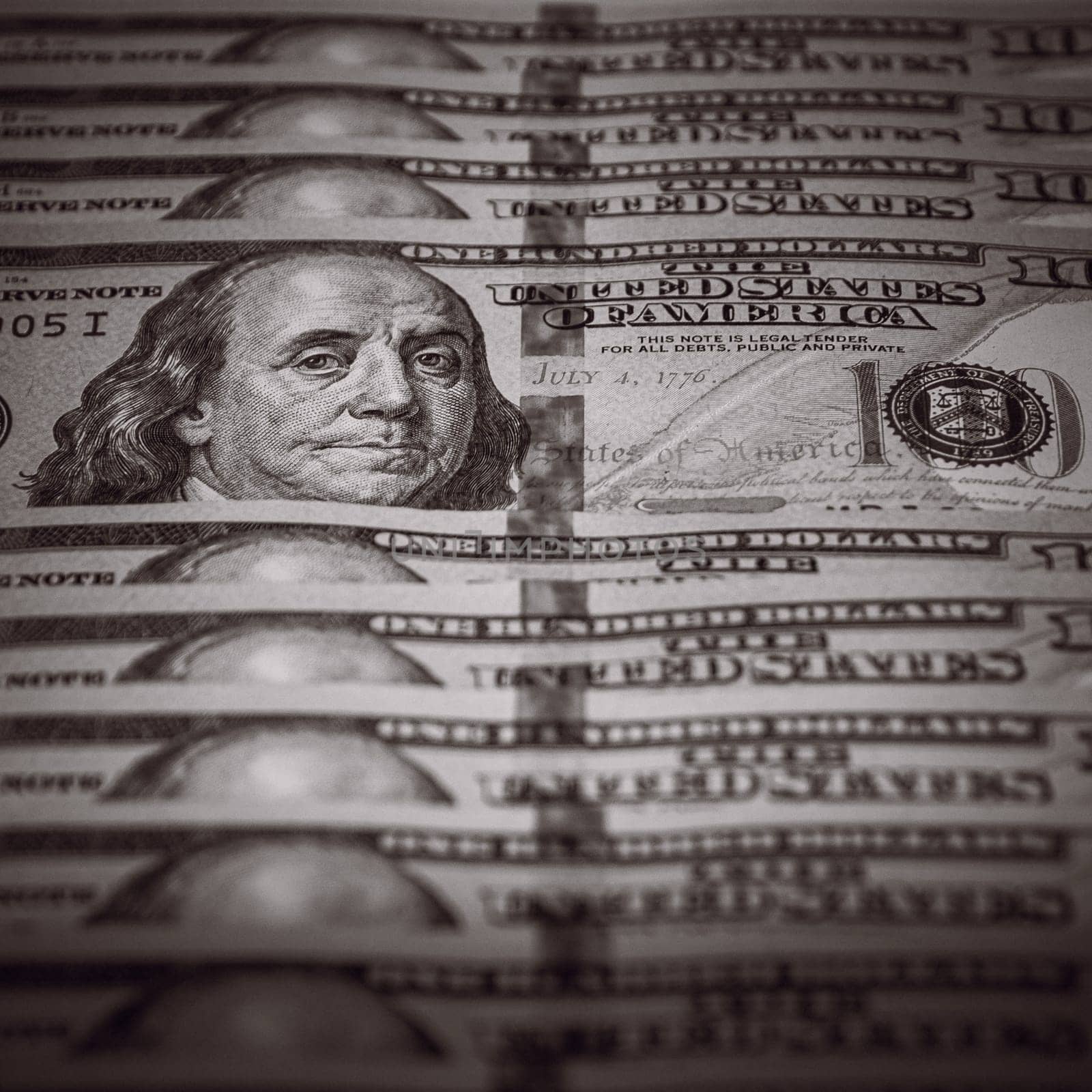 One hundred dollar bills are in a row, one stands out, selective focus. Style black and white.