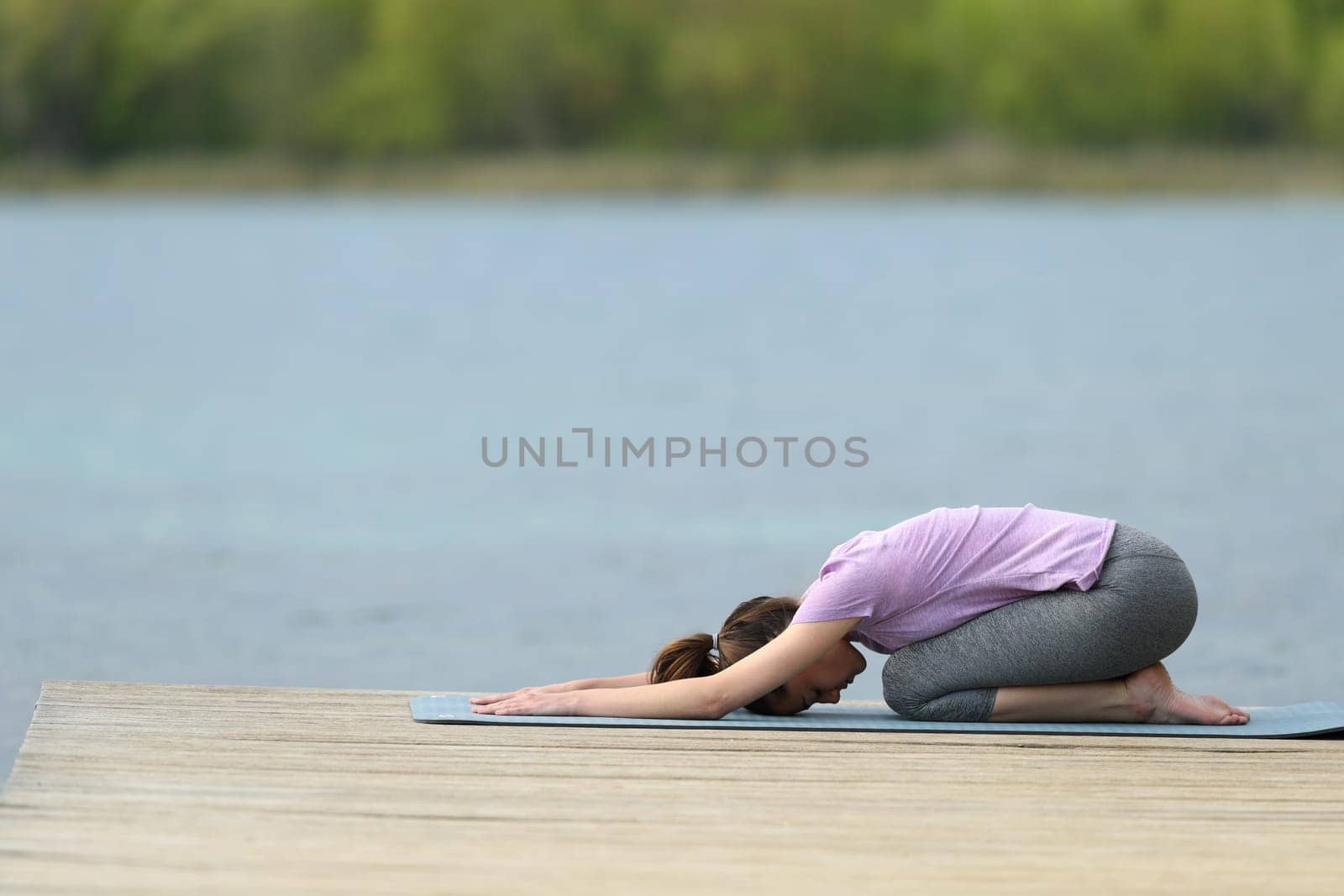 Profile of a yogi doing yoga exercise in a lake pier
