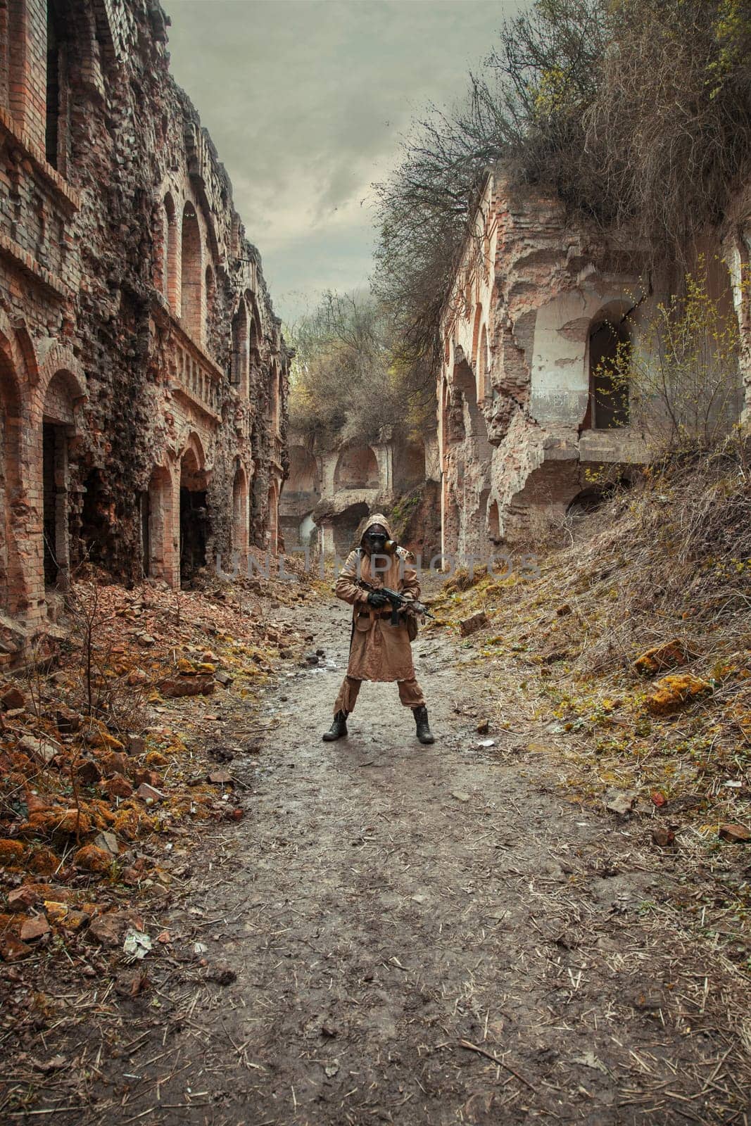 Nuclear post-apocalypse. Sole survivor in tatters and gas mask on the ruins of the destroyed city