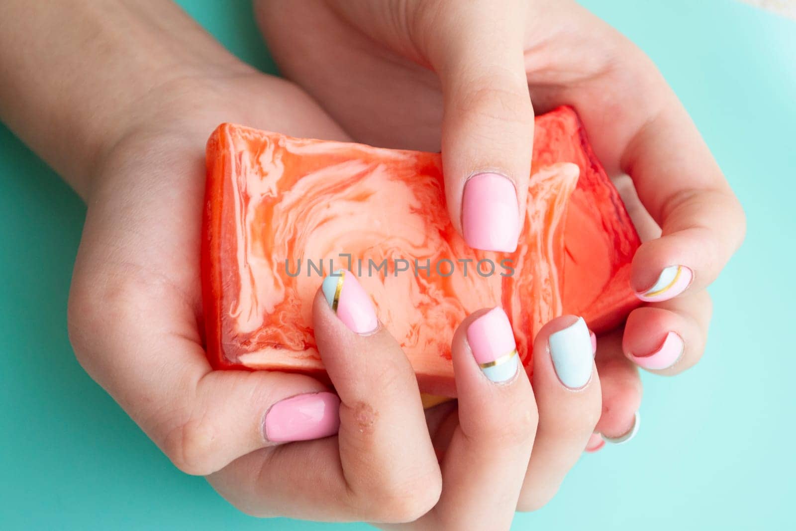 woman hands with natural hand made soap on teal background