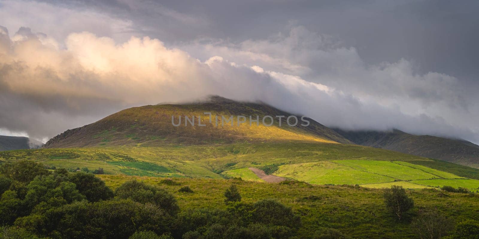 Beautiful sunrise, sunlight illuminating mountain and cloud on it, foothill of Carrauntoohil, MacGillycuddys Reeks mountains, Ring of Kerry, Ireland