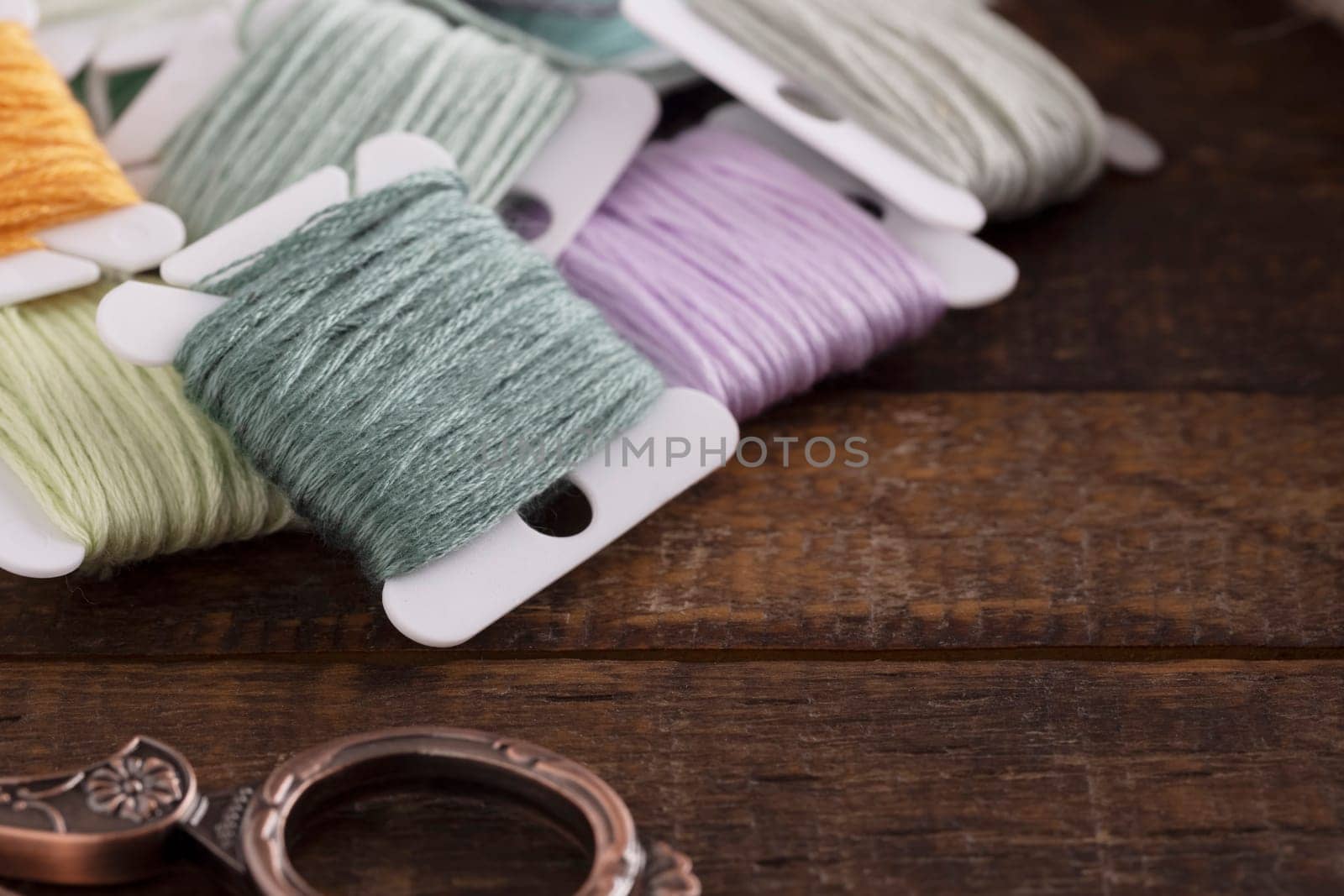 Colorful cotton embroidery floss with vintage style scissors on wooden table.