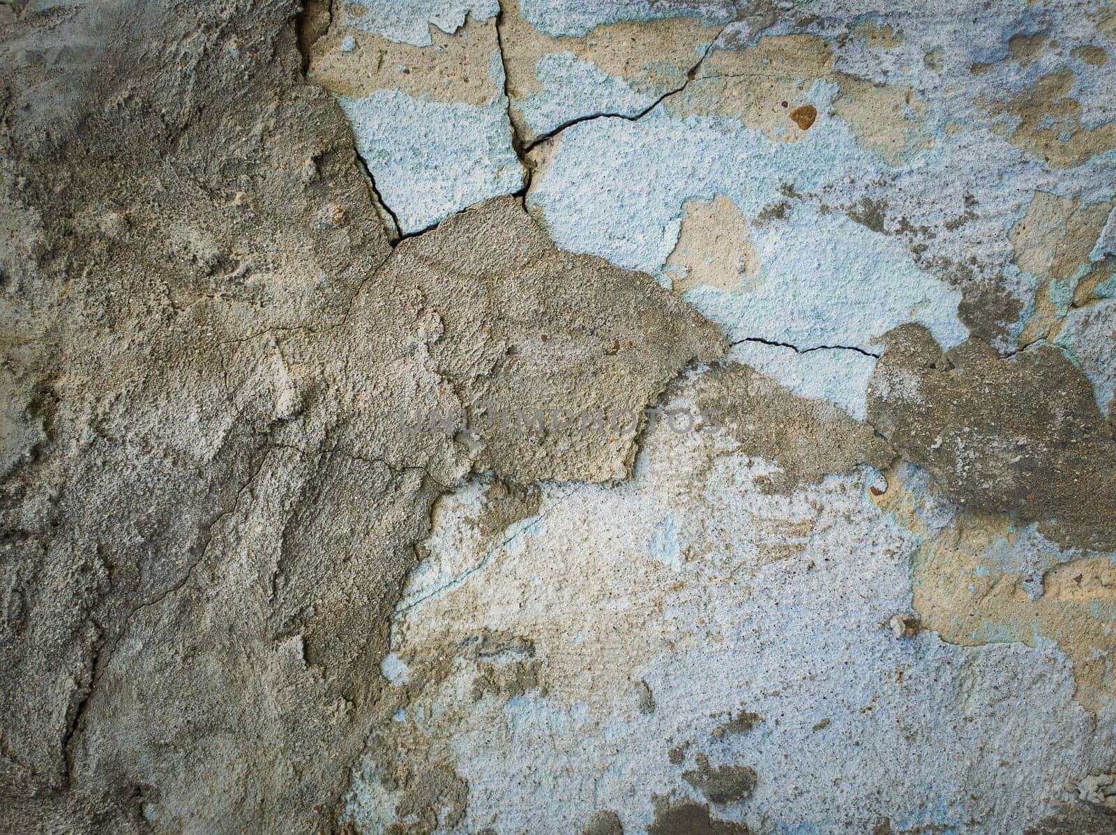 Weathered and cracked concrete wall maintained through time with blue lime and different mortar mixes. Peeling plaster from cement structure surface. Construction element, abstract texture background.