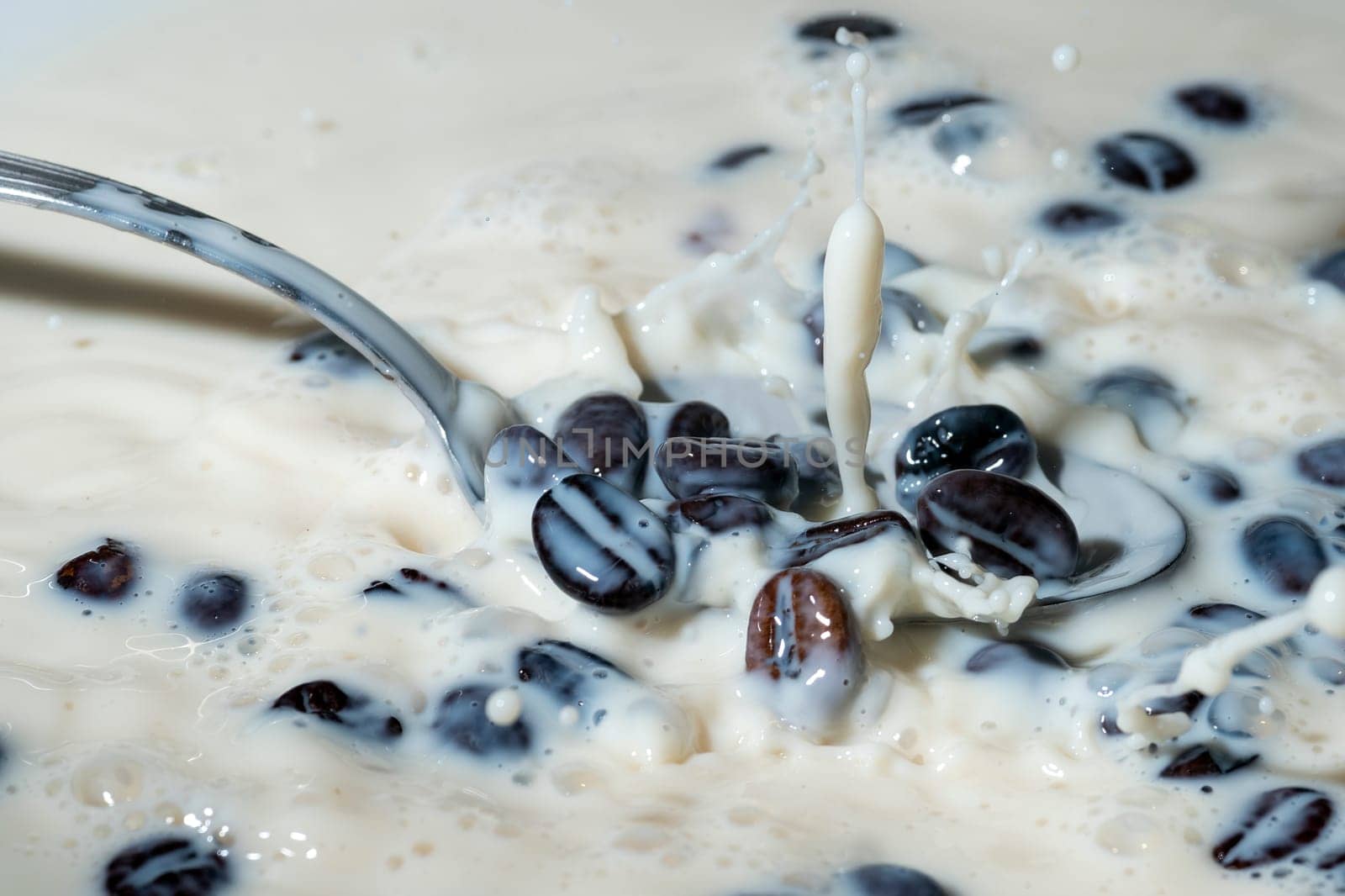 Coffee beans falling on the milk splash. Cup of milk. Concept photography.