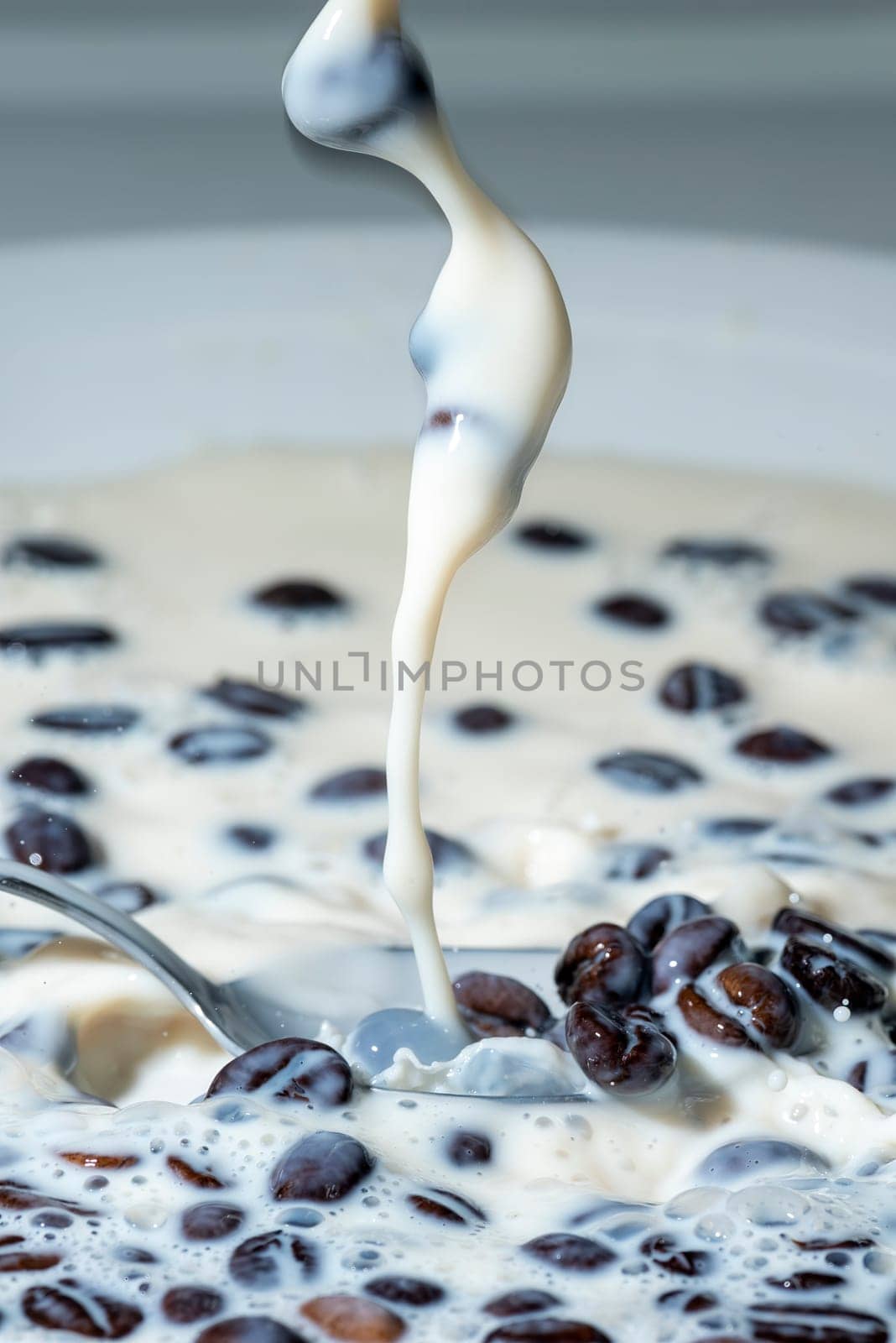 Coffee beans falling on the milk splash. Cup of milk. Concept photography.