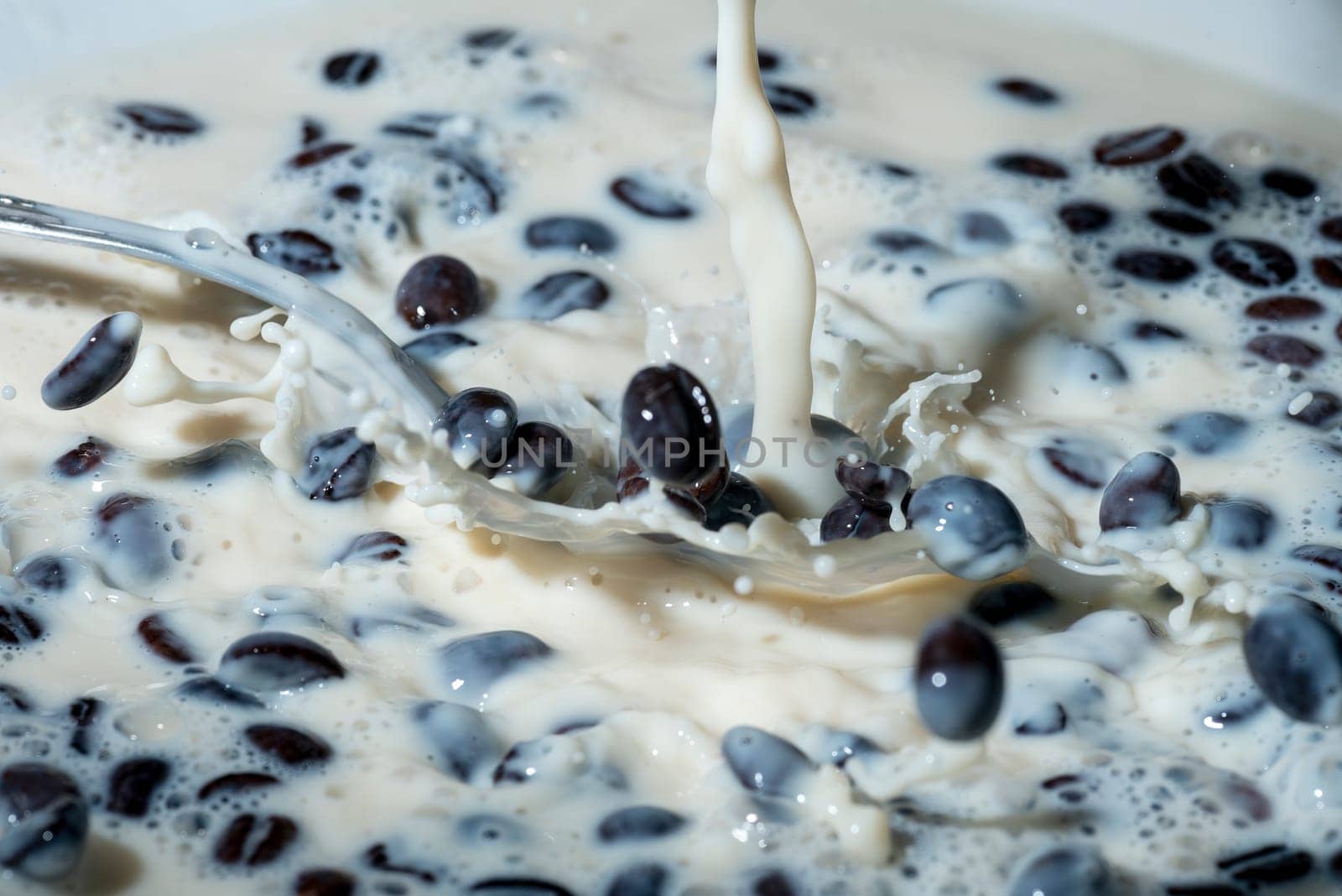 Coffee beans falling on the milk splash. Cup of milk. Concept photography.
