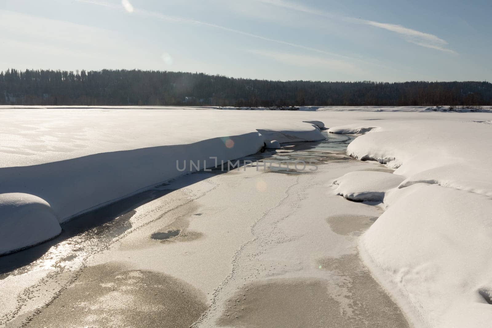 thawed patch with water on river among snow.