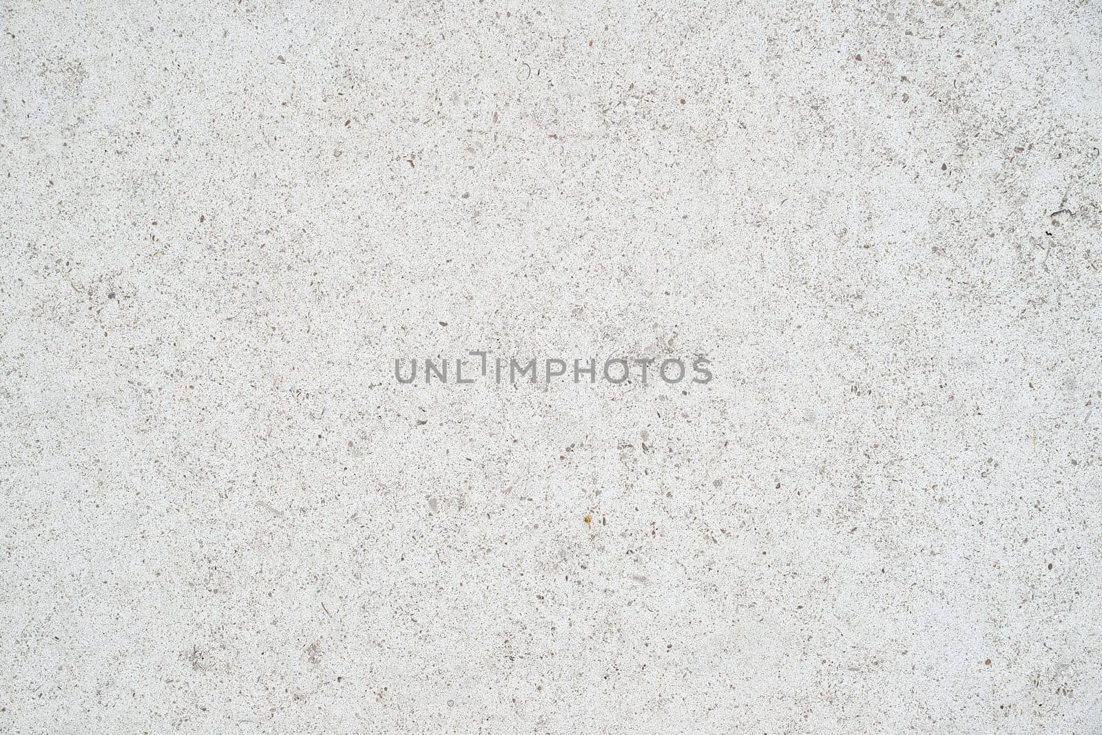 The subtle white textured surface of an external concrete wall. The wall is lightly speckled.