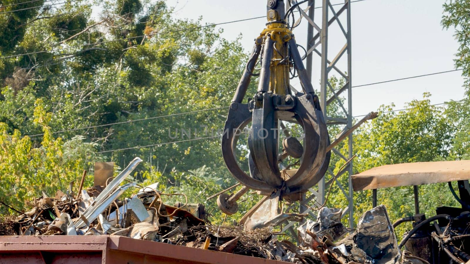 Photo of metal claw lifting metal on scrapyard