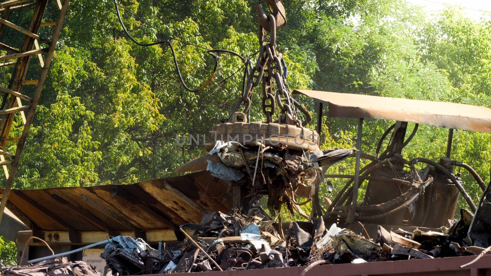 Electric magnet sorting metal waste from other rubbish on scrapyard