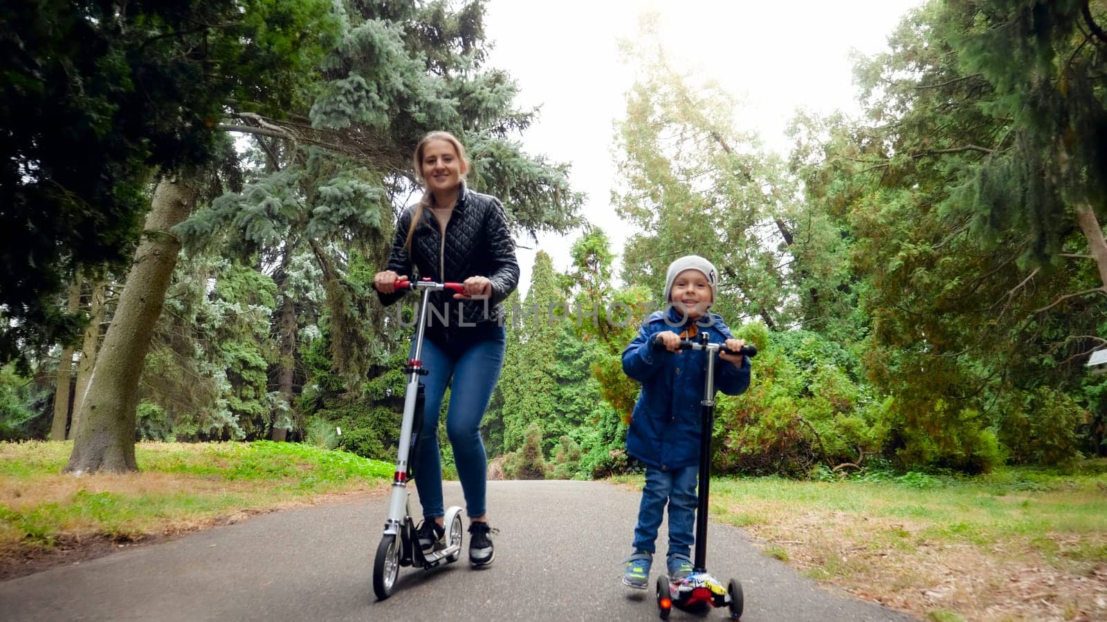 Happy smiling family riding on scooters at autumn park.