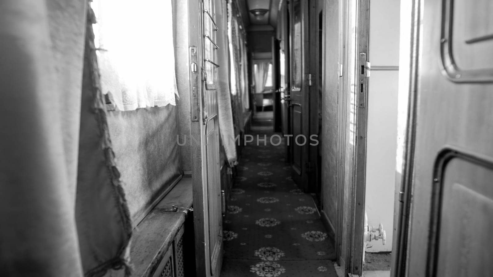 Black and white photo of long narrow corridor in vintage train car