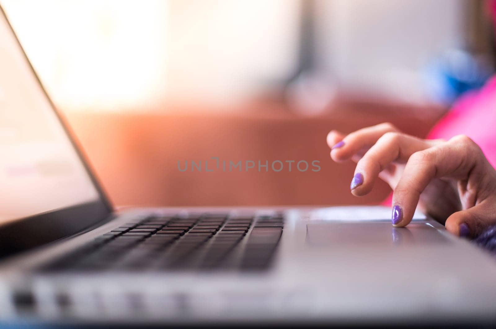 Girl with purple fingernails is using her laptop at home on the couch