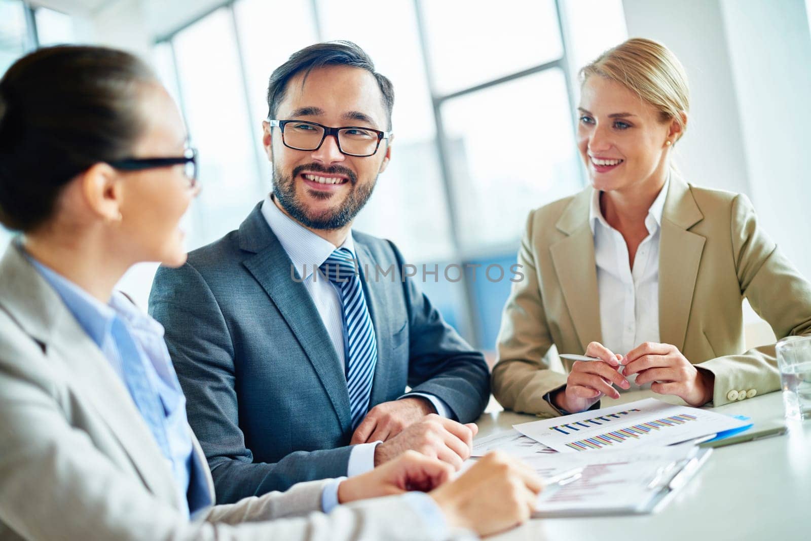 Happy businessmen and two pretty employees communicating at meeting