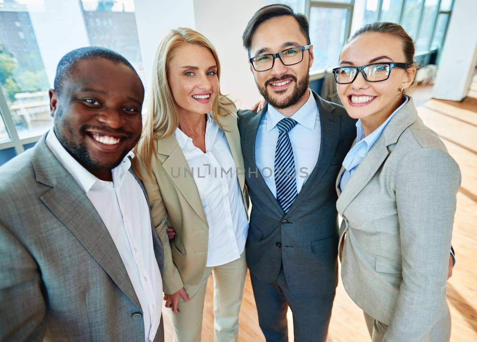 Happy business partners in formalwear looking at camera in office