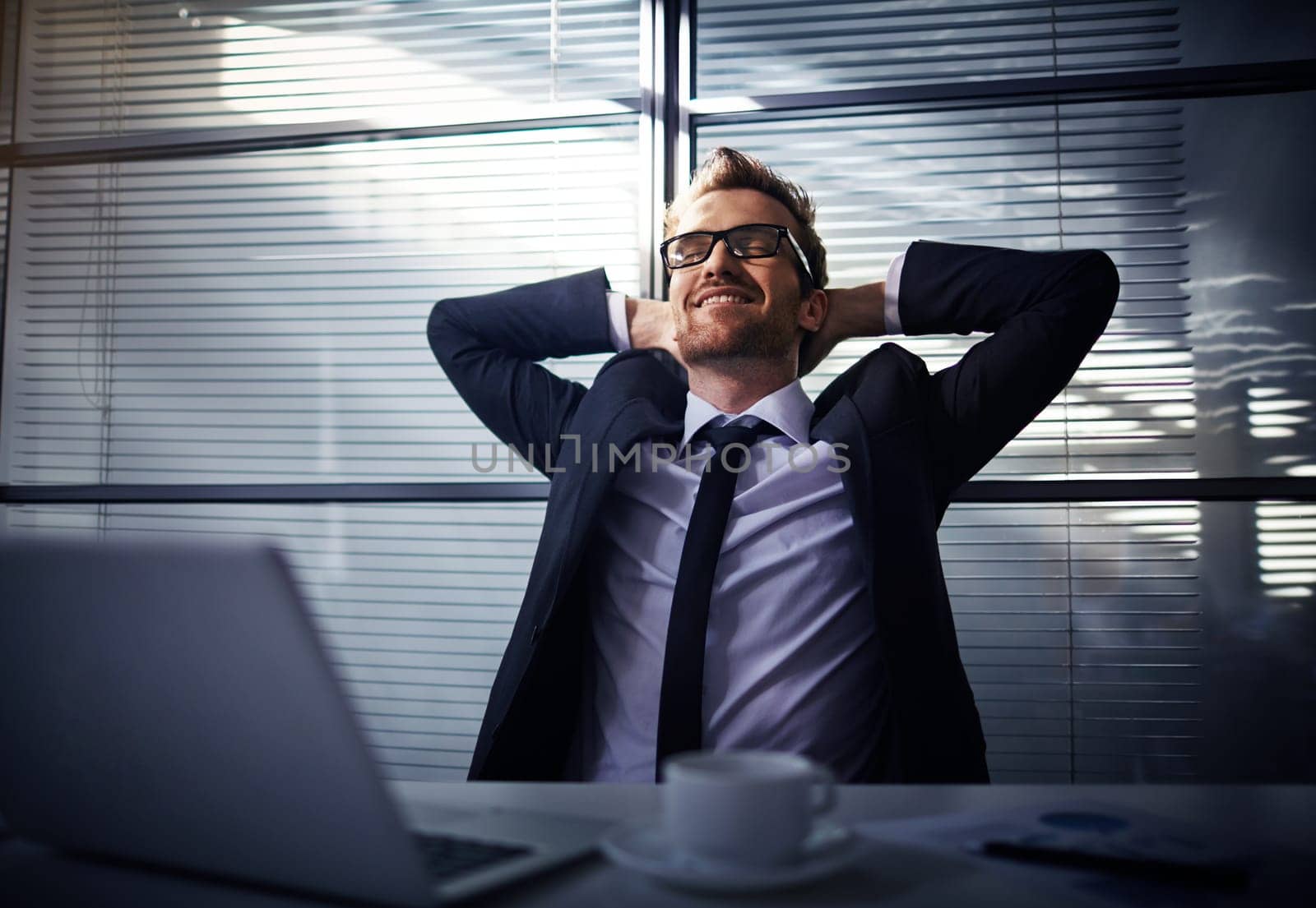 Happy young businessman dreaming in office