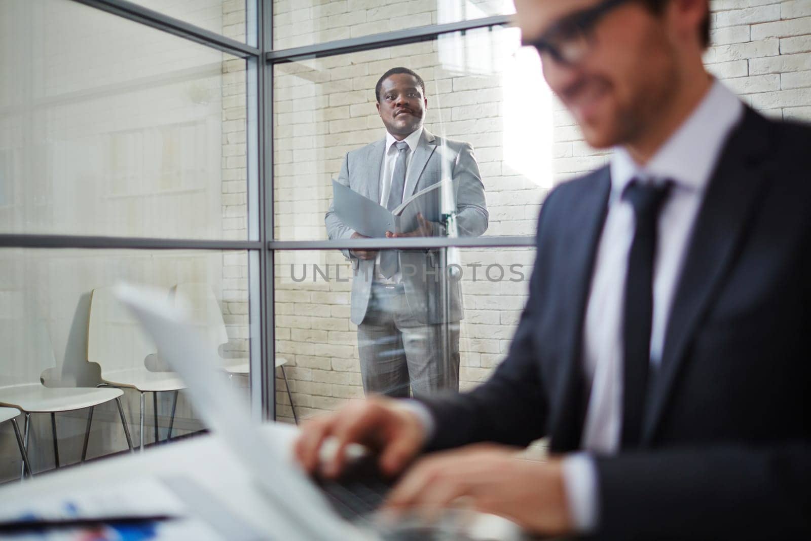 African businessman in suit looking at colleague working in office