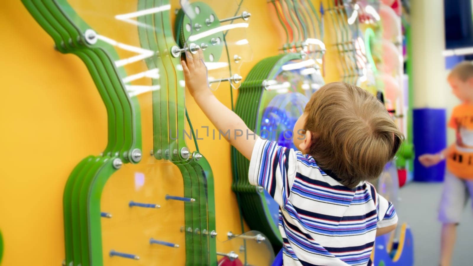 Cute little boy playing with educational mechanism in museum of science.