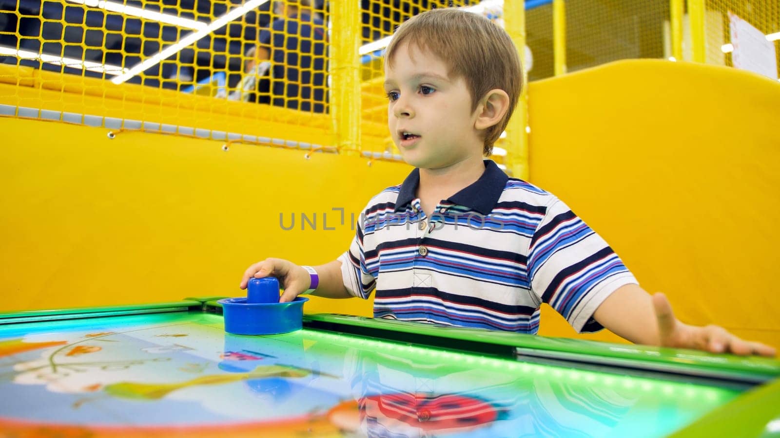 Portrait of little boy playing in air hockey at amusement park