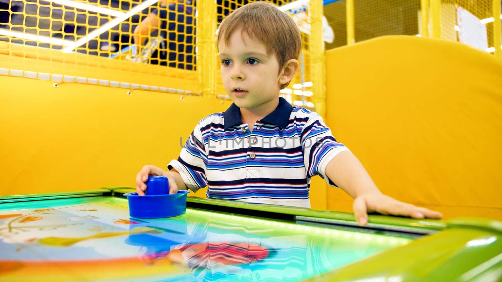 Portrait of little toddler boy playing in air hockey.