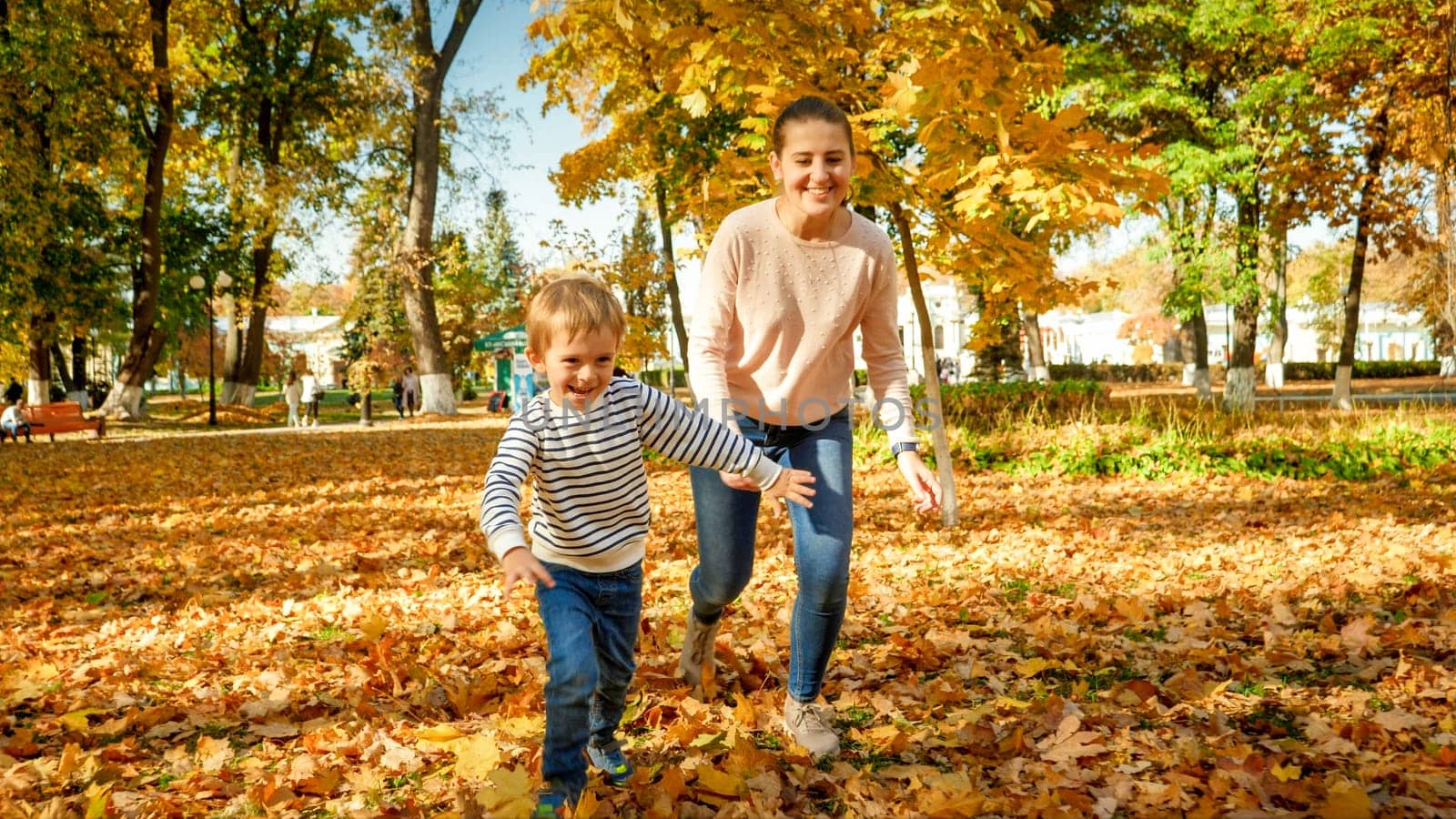 Happy laughing family running and palying at autumn park.