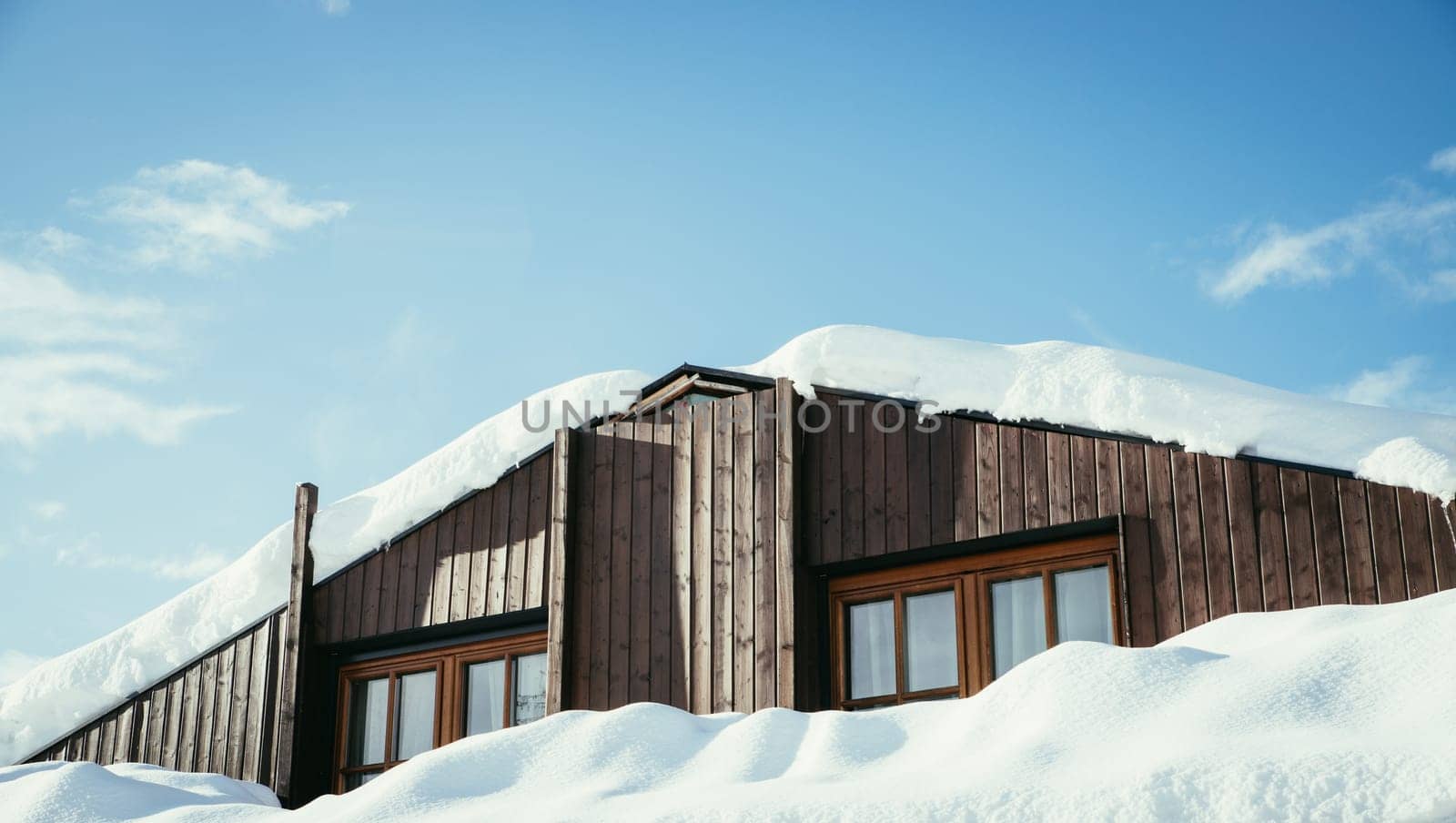 Modern wood house in the winter: Snow on the roof, blue sky