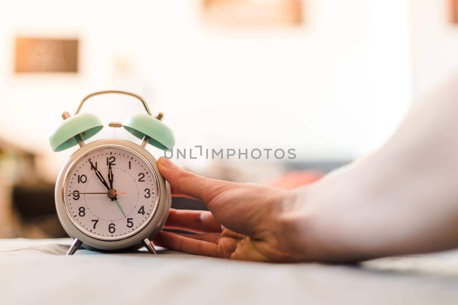 Man is pushing an alarm clock, sunshine in the morning, blurry background
