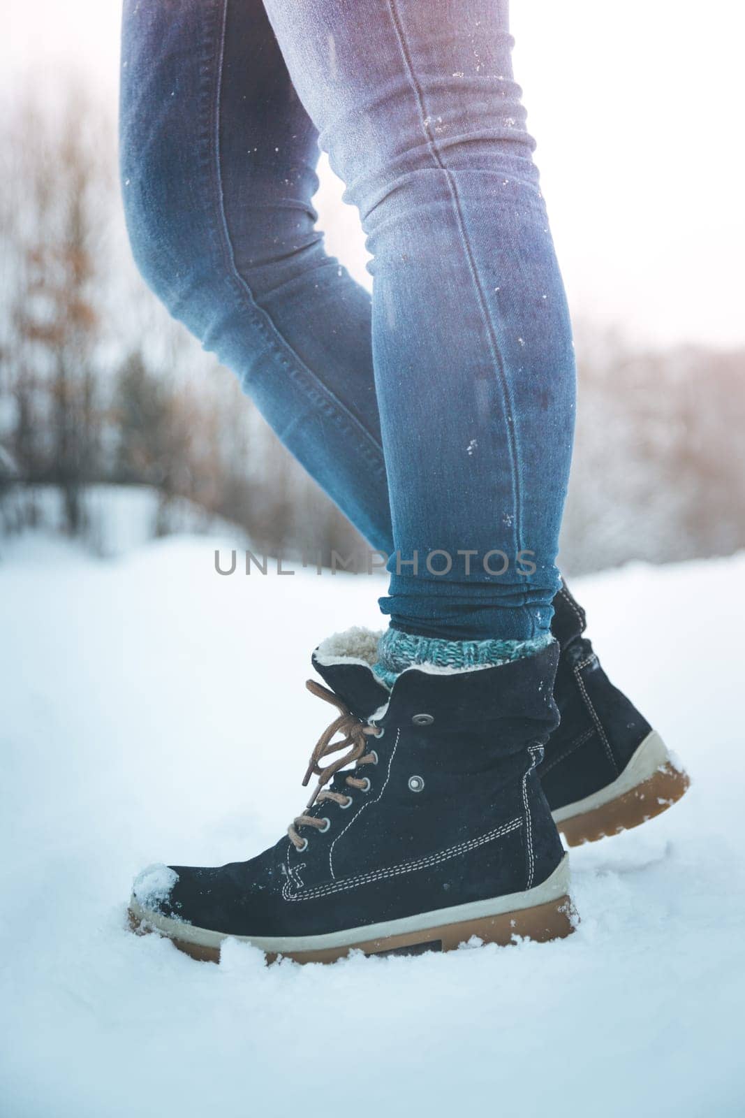 Girl in blue jeans is hiking in the wintertime, legs and shoes