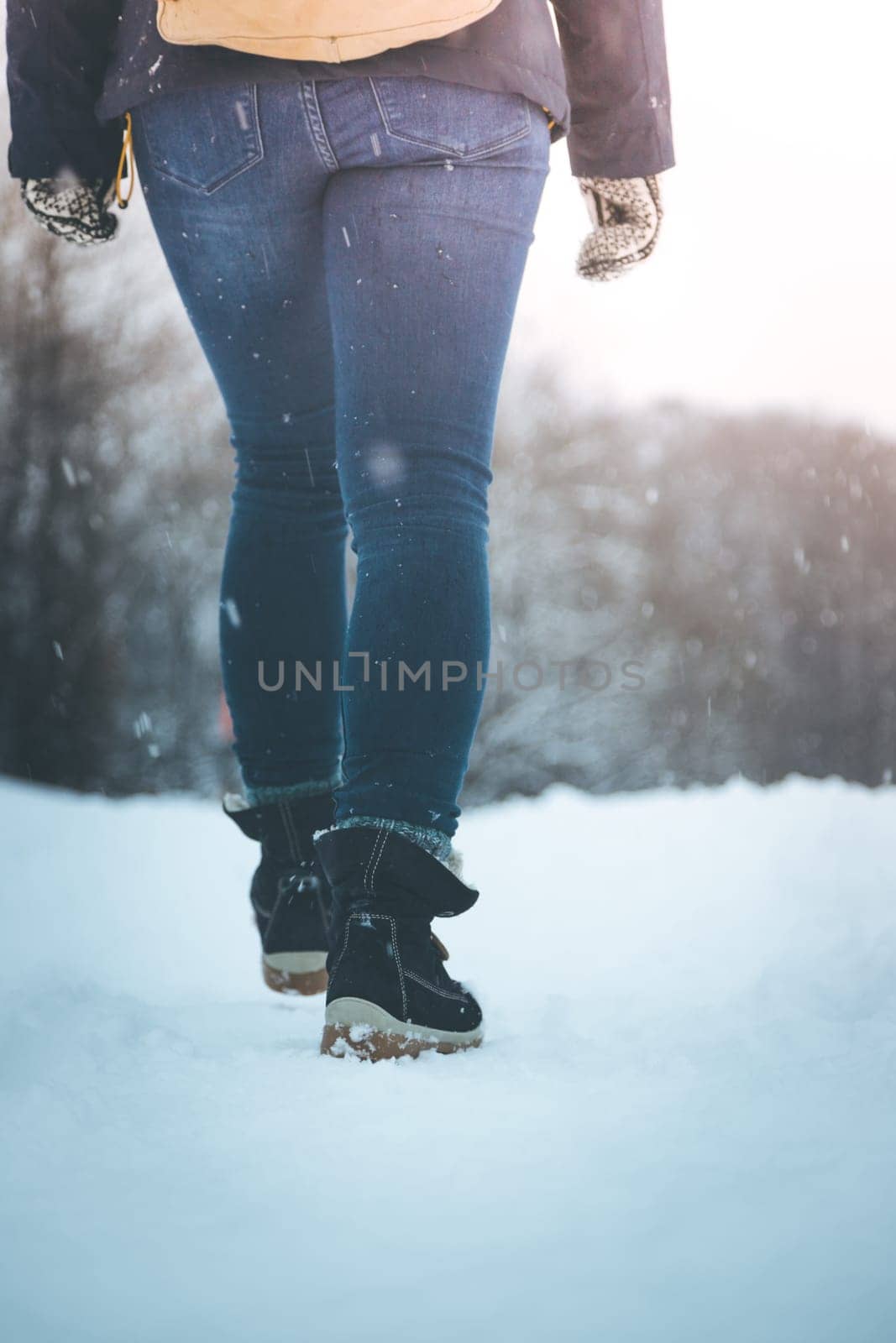Girl in blue jeans is hiking in the wintertime, legs and shoes