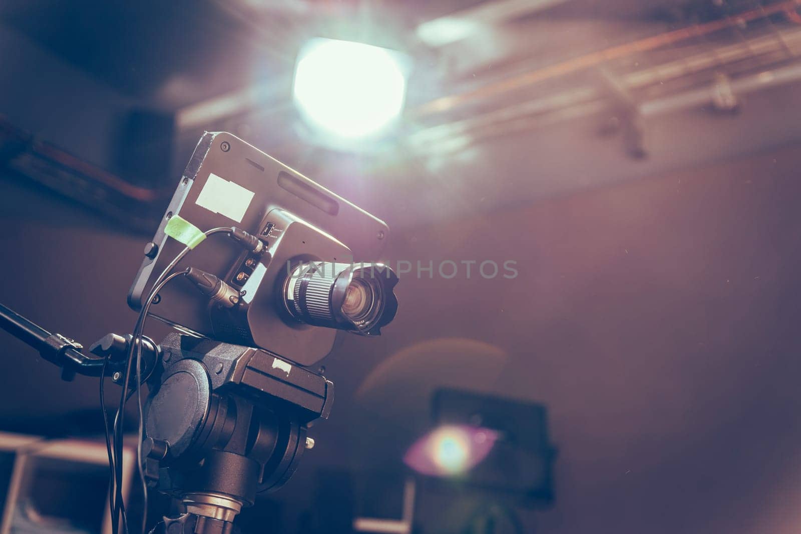 Film camera on a tripod in a television broadcasting studio, spotlights and equipment
