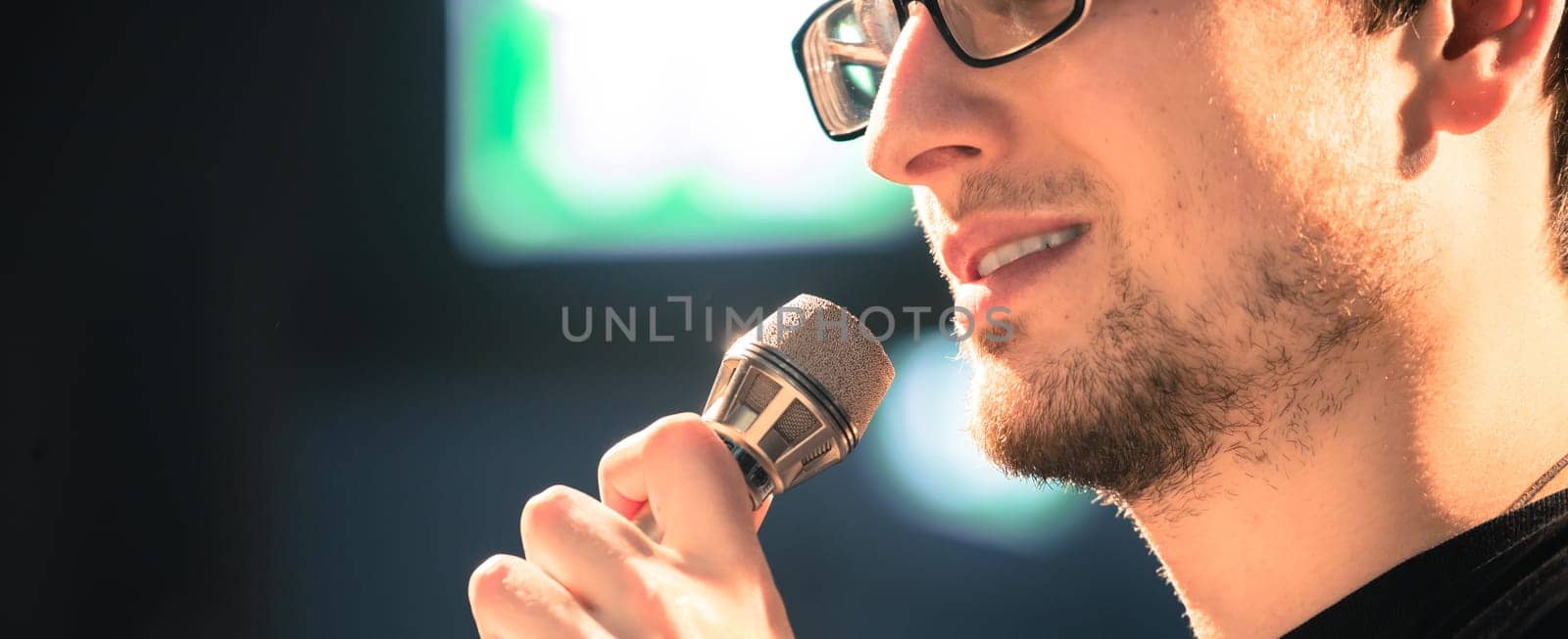 Young man on the stage is talking into a microphone, speech
