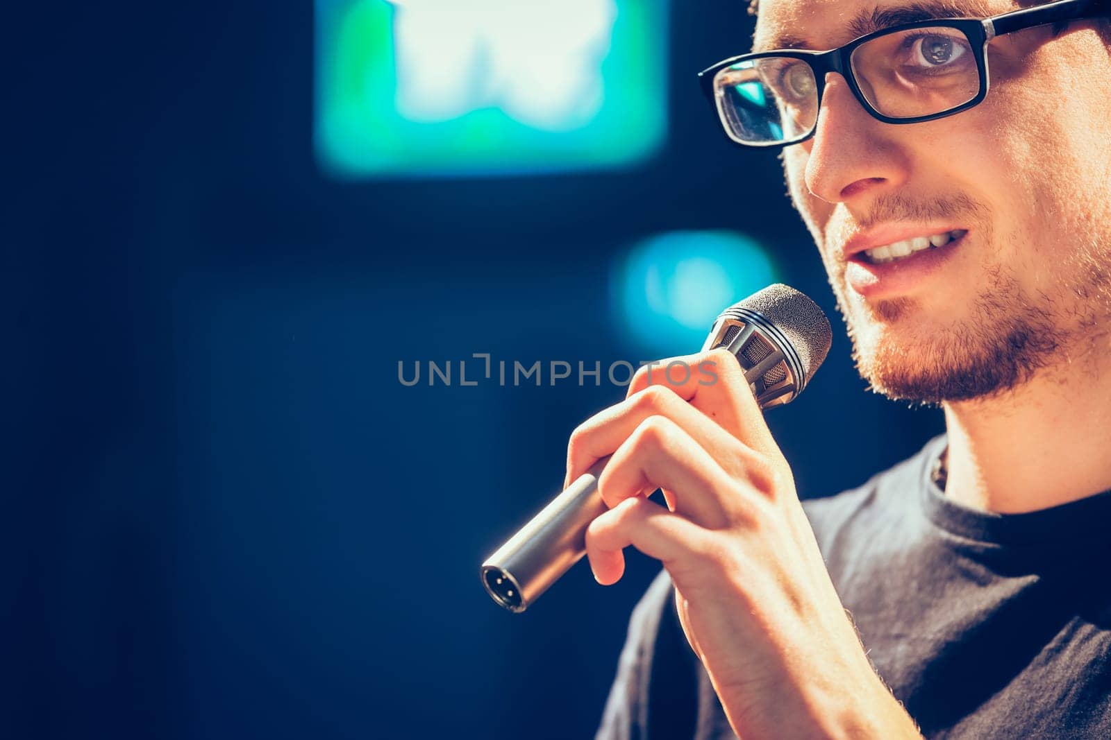 Young man on the stage is talking into a microphone, speech