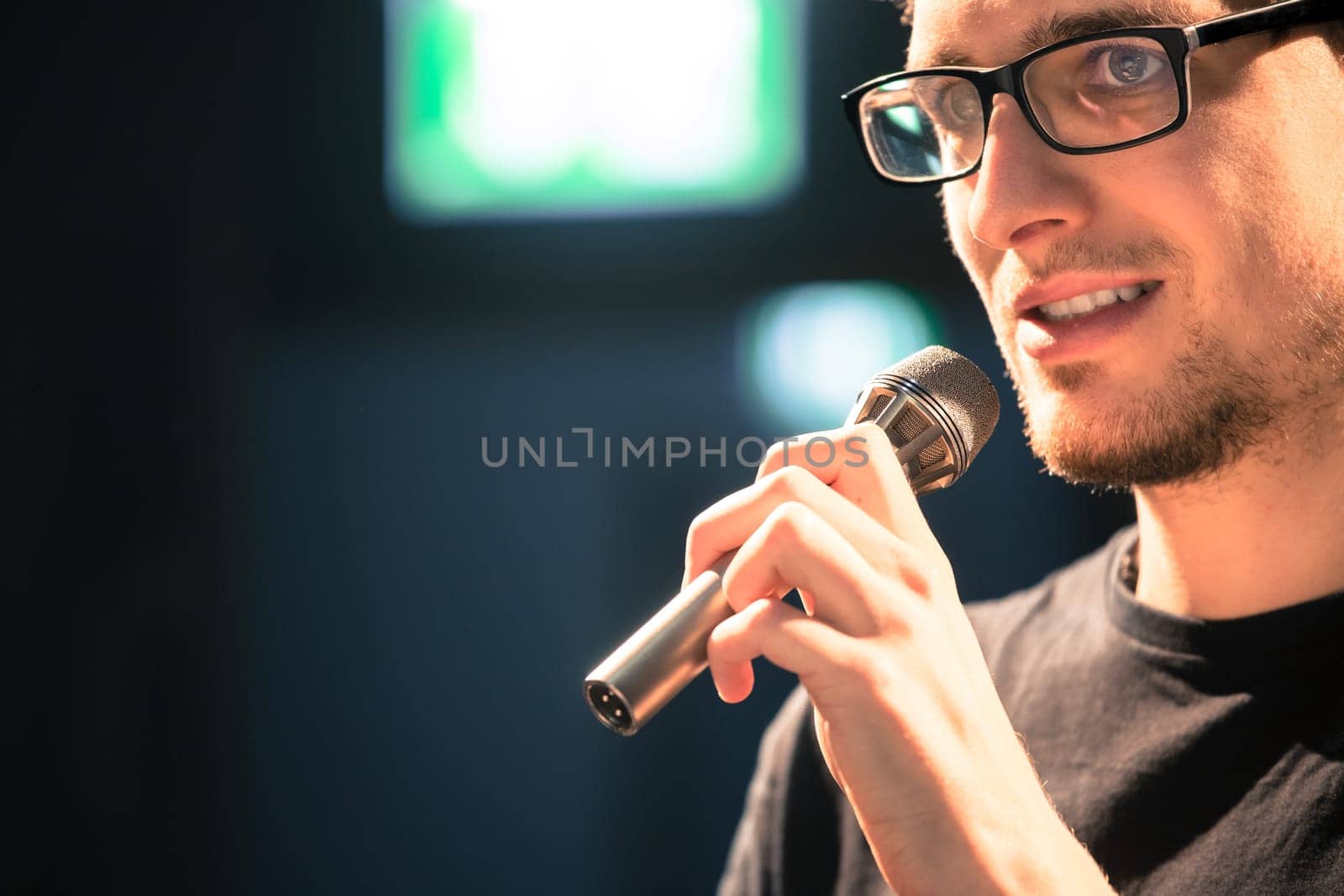 Young man on the stage is talking into a microphone, speech