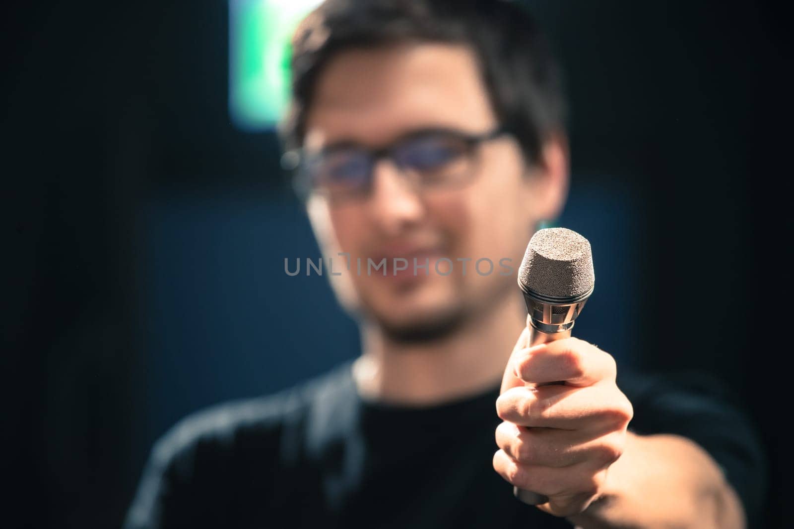 Young man on the stage is talking into a microphone, speech, face is blurry