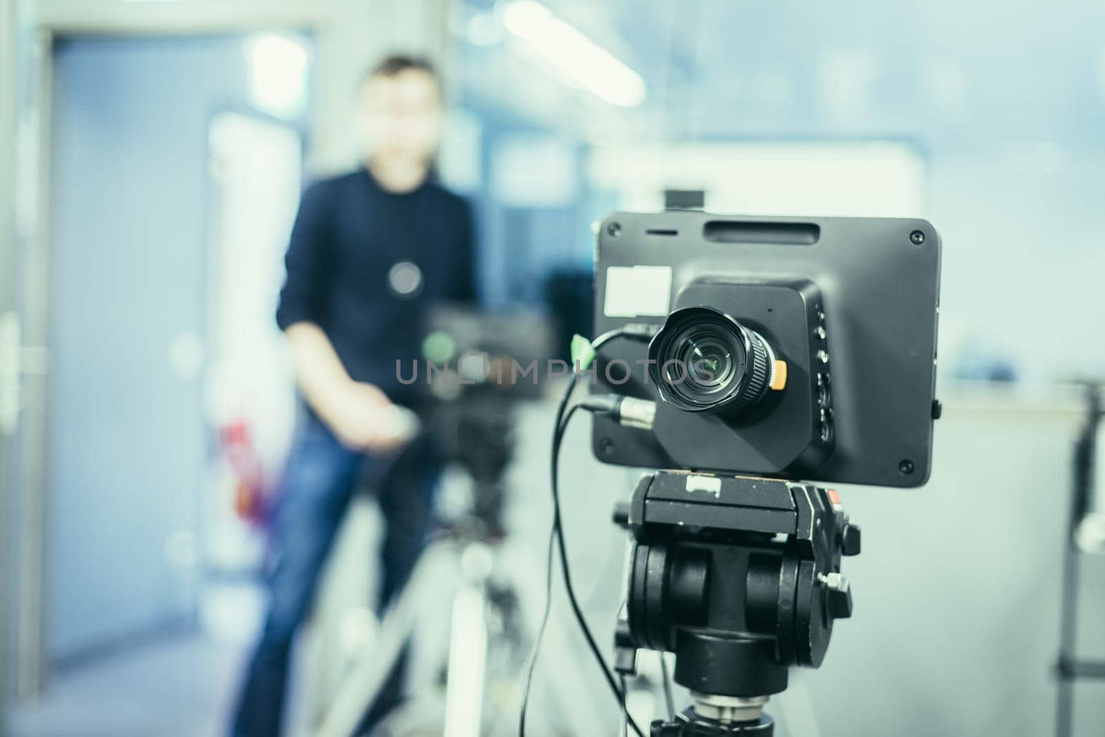 Lens of a film camera in an television broadcasting studio, spotlights and equipment, cameraman in the blurry background
