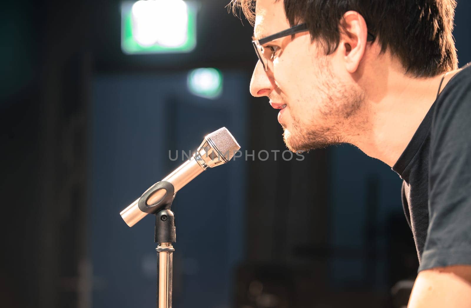 Young man on the stage is talking into a microphone, speech