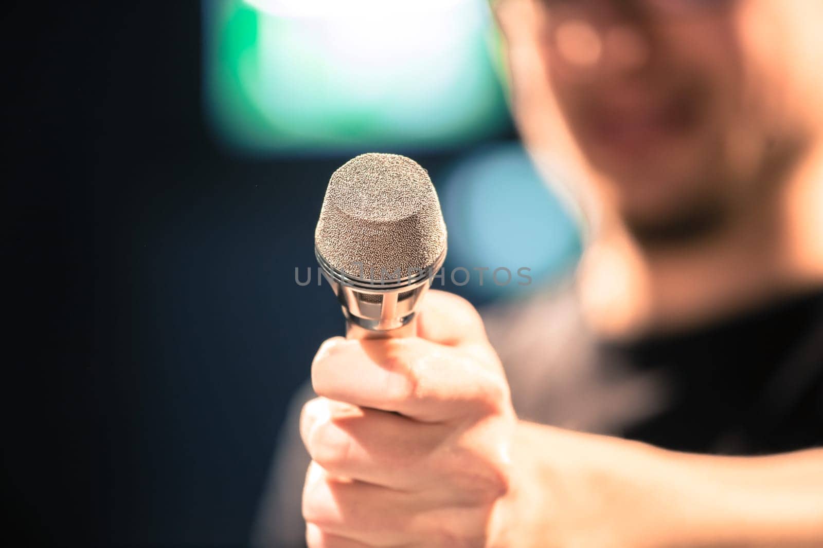 Young man on the stage is talking into a microphone, speech, face is blurry