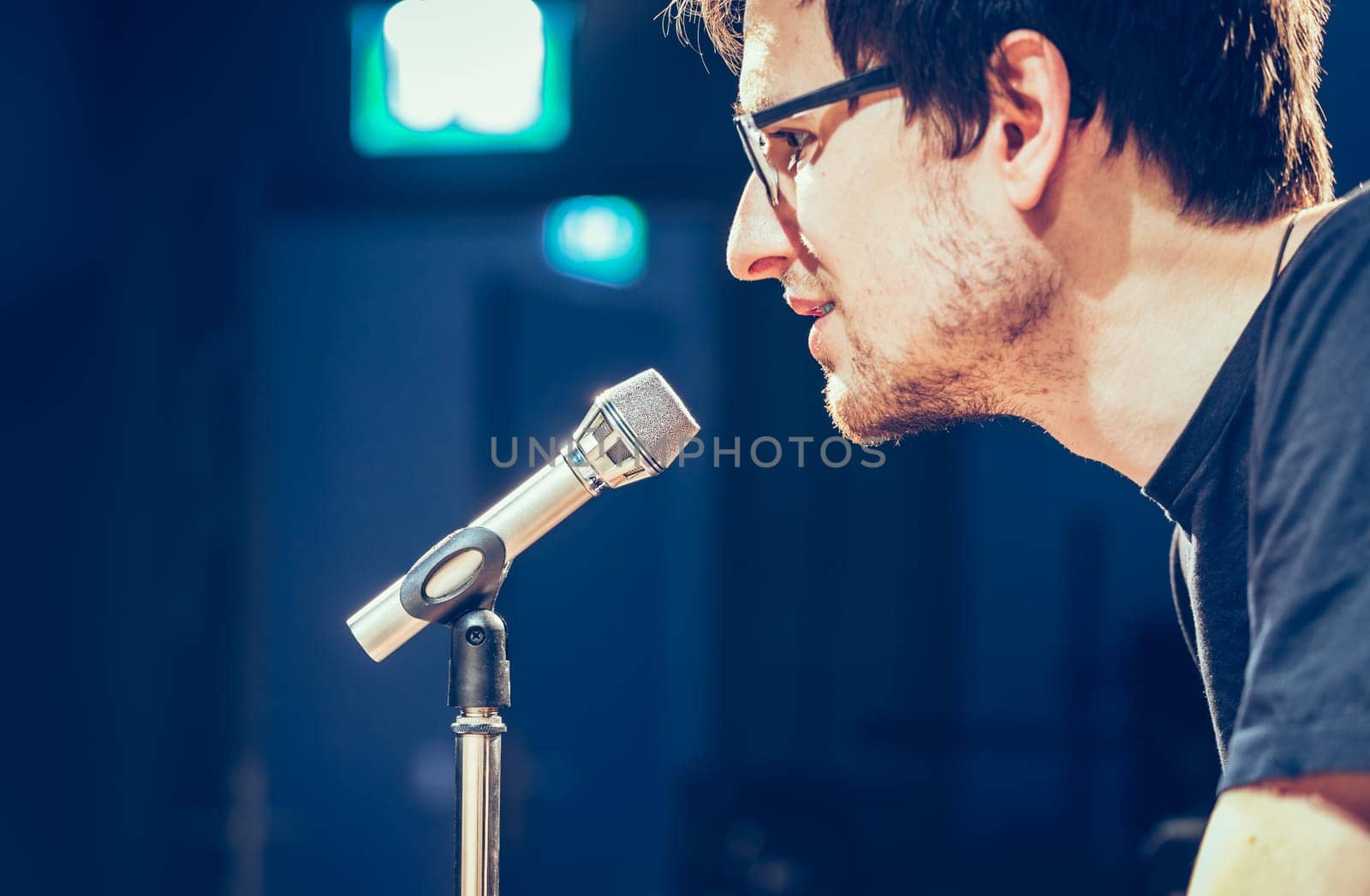 Young man on the stage is talking into a microphone, speech