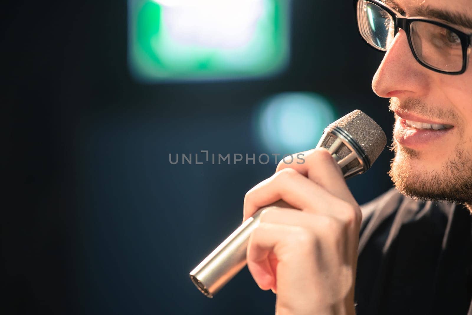 Young man on the stage is talking into a microphone, speech