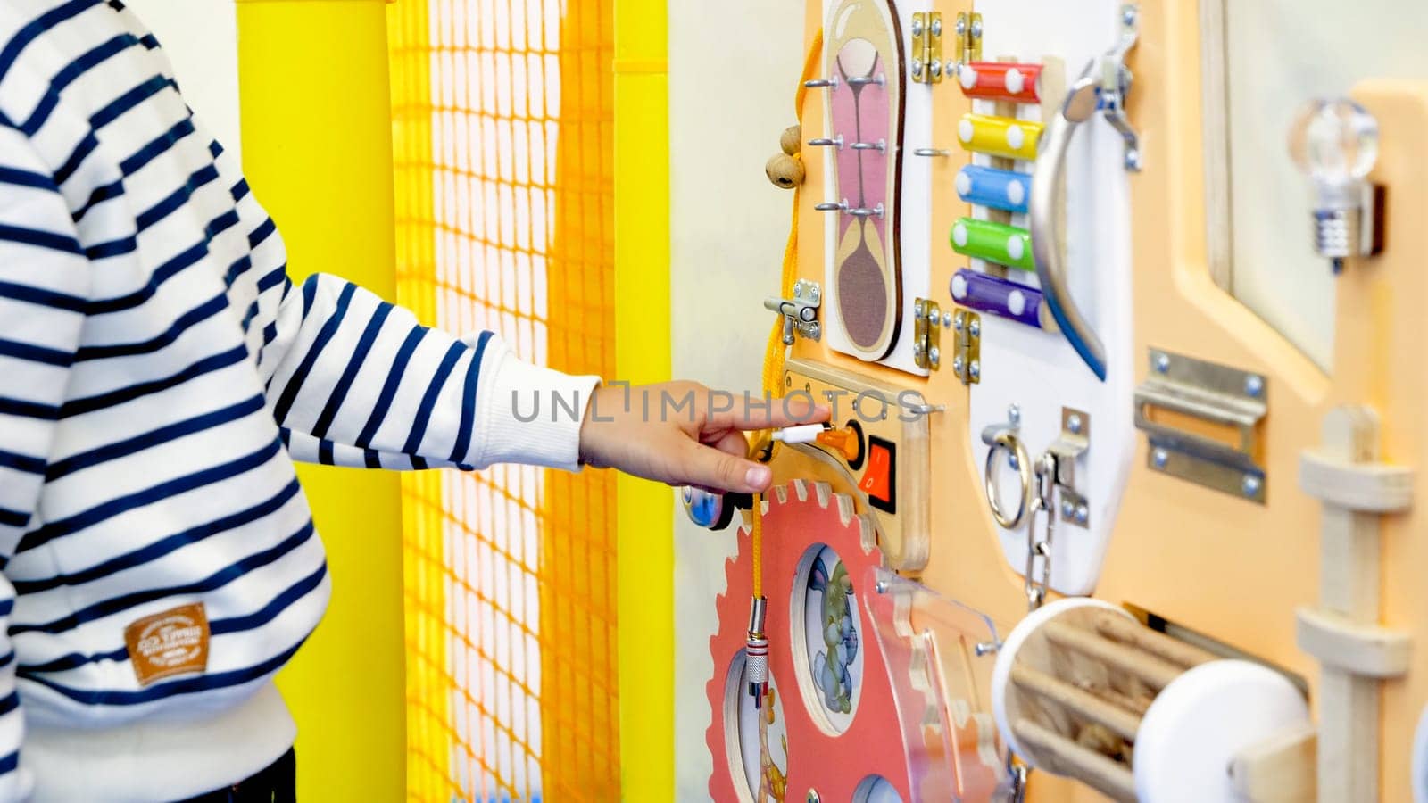 Closeup image of little toddler boy playing on busy board for children education.