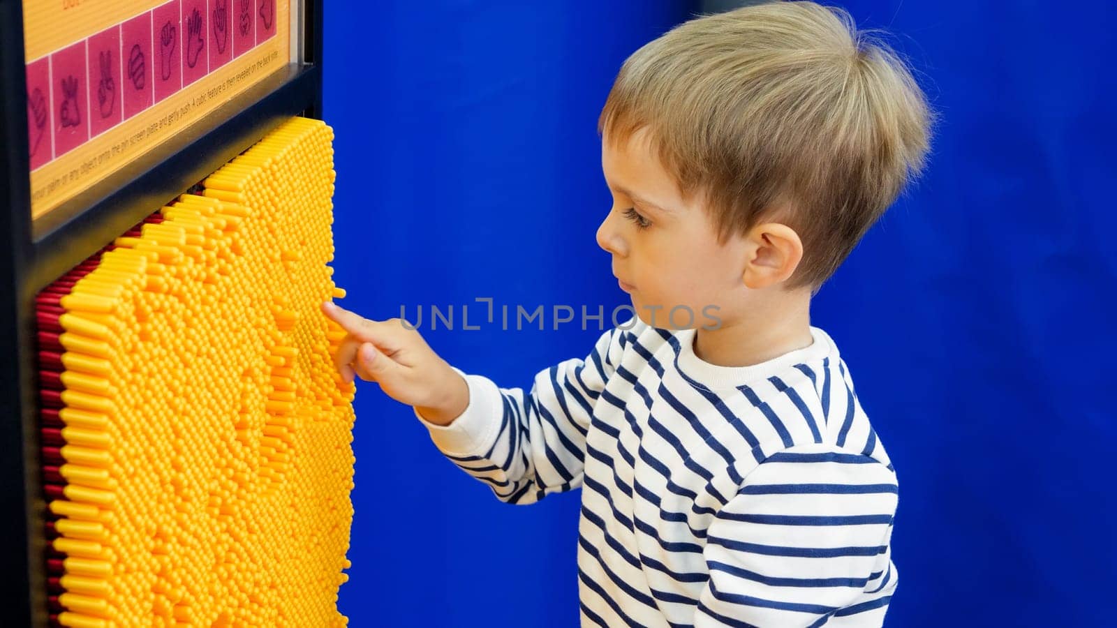 Portrait of little toddler boy playing educational game in museum of science.