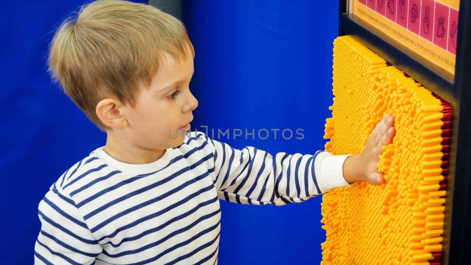 Portrait of little boy living print of his hand on educational game at amusement park.