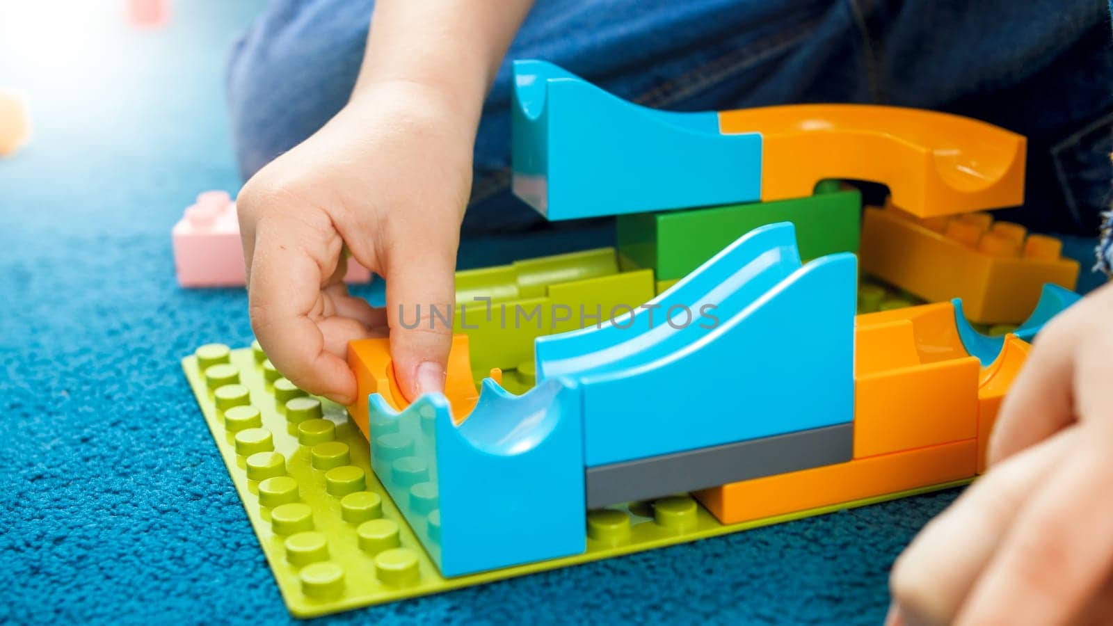 Closeup image of boys hand building toy track using constructor blocks.